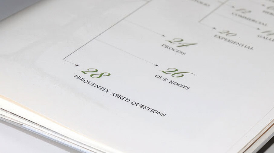 Close-up of a table of contents page in a NatureMaker brochure. The page shows elegant typography with green numerals and black serif text, listing entries such as “24 Process,” “26 Our Roots,” and “28 Frequently Asked Questions,” with arrows guiding the reader’s navigation through the sections.