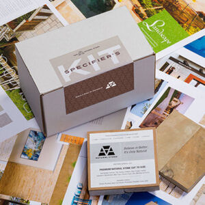 Specifier’s Kit from Natural Stone displayed on a spread of colorful printed brochures and samples. The kit includes a branded shipping box labeled 'Specifier’s Kit' with the Natural Stone logo, and a smaller box in the foreground labeled 'Premium Natural Stone Cut to Size' with the slogan 'Believe in Better. It’s Only Natural.
