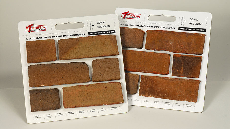 Two sample boards from Thompson Building Materials showcasing thin brick veneer pieces. One board is labeled 'Boral Buckskin' and the other 'Boral Regency.' Each board features six mounted brick samples in varying earthy tones and textures, along with product identification details and the slogan 'The All Natural Clear Cut Decision.