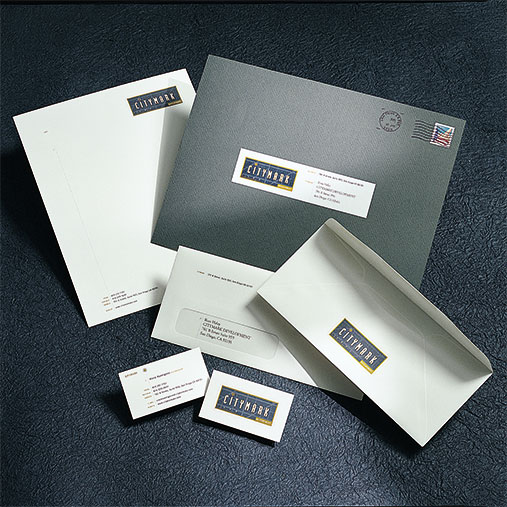 Corporate stationery set for Citymark displayed on a dark textured surface. The branded materials include business cards, letterhead, envelopes, and a large mailing envelope, all featuring the Citymark logo with a navy blue and gold color scheme. The layout emphasizes a clean, professional identity system for business correspondence.