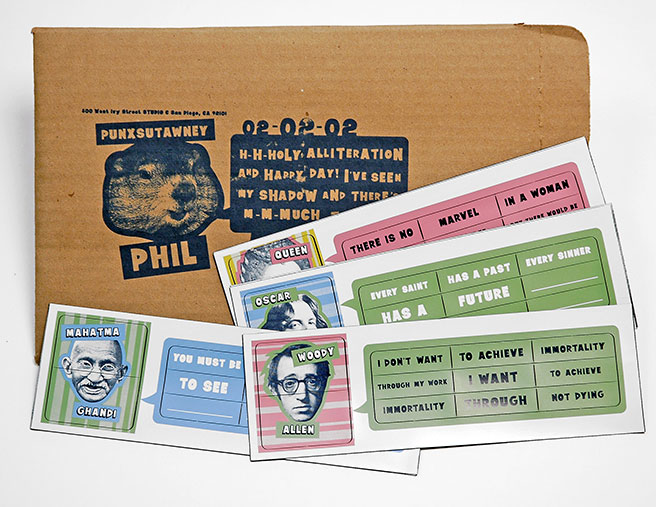 A set of colorful magnetic poetry strips with illustrated portraits and famous quotes from figures like Mahatma Gandhi, Woody Allen, and Oscar Wilde. The magnets are arranged on top of a kraft envelope labeled with “Punxsutawney Phil” and a humorous message referencing Groundhog Day, dated 02-02-02. The designs are playful, using bold fonts and varied color backgrounds.