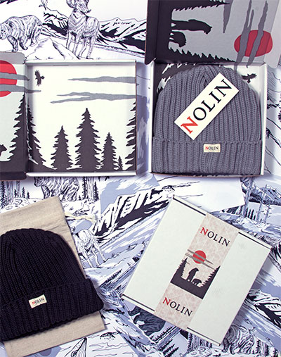 Branded packaging and knit beanies from Nolin arranged on illustrated paper featuring wilderness scenes with wolves, trees, and mountains. The display includes two beanies—one gray and one black—each with a Nolin tag, alongside custom boxes and printed wraps with the Nolin logo and a red sun graphic in a nature-themed design.